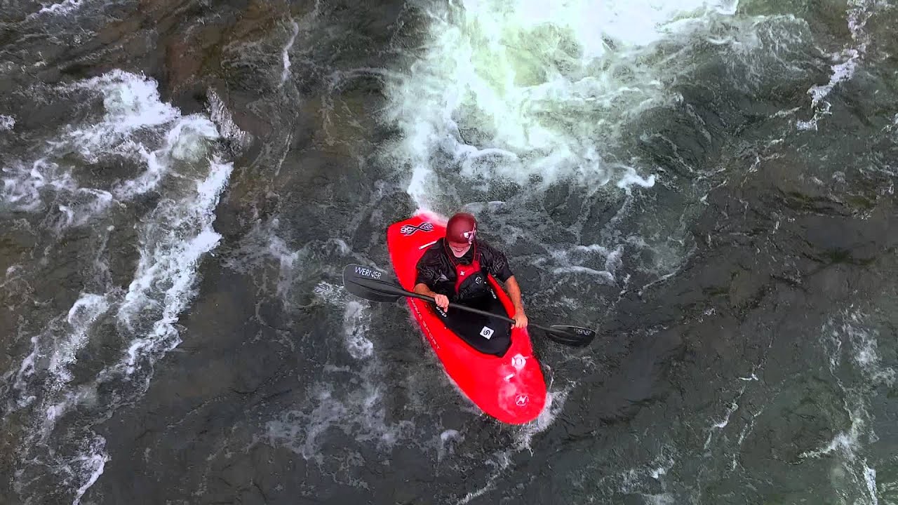 A red kayak in whitewater, photographed from directly above